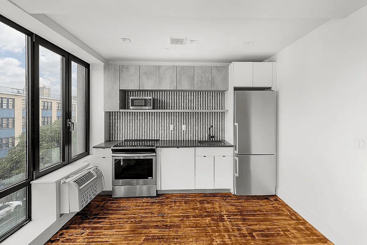 A modern kitchen with a wooden floor and white walls.