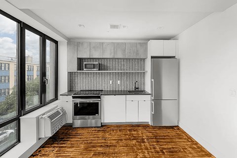 A modern kitchen with a wooden floor and white walls.