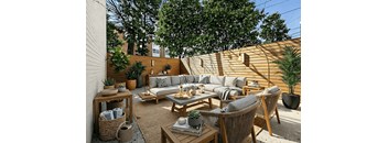 A patio with a couch, chairs, and a table with a potted plant on it.