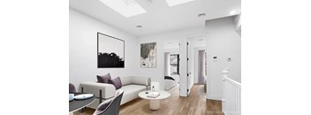 A living room with a white couch and a painting on the wall.