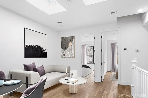 A living room with a white couch and a painting on the wall.