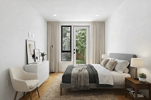A well-lit bedroom with a large bed and a chair.