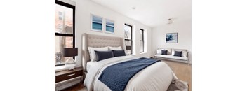 A bedroom with a large bed and a window overlooking a cityscape.