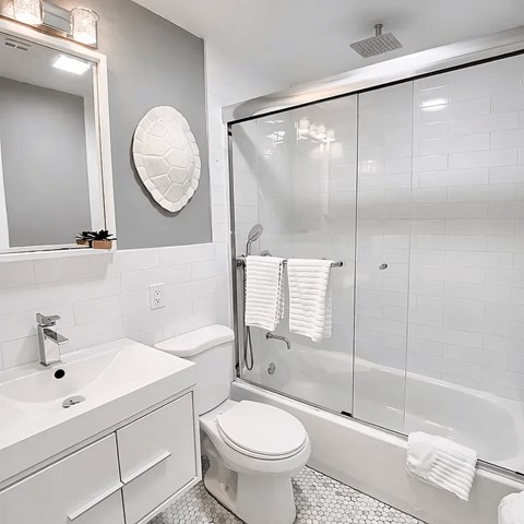 A white bathroom with a toilet, sink, and shower.