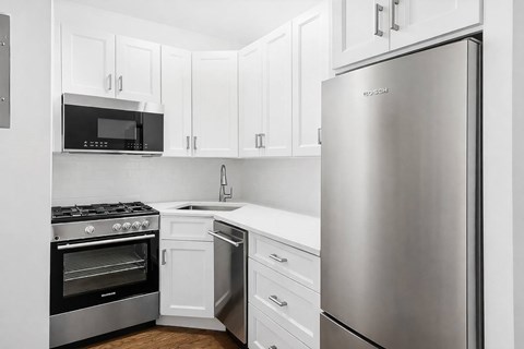 A kitchen with a stainless steel refrigerator, oven, and microwave.