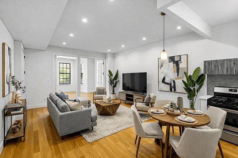 A modern living room with a grey sofa, a wooden coffee table, and a dining table set for six.