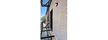A brick wall with a black gate and a small square light fixture on it.