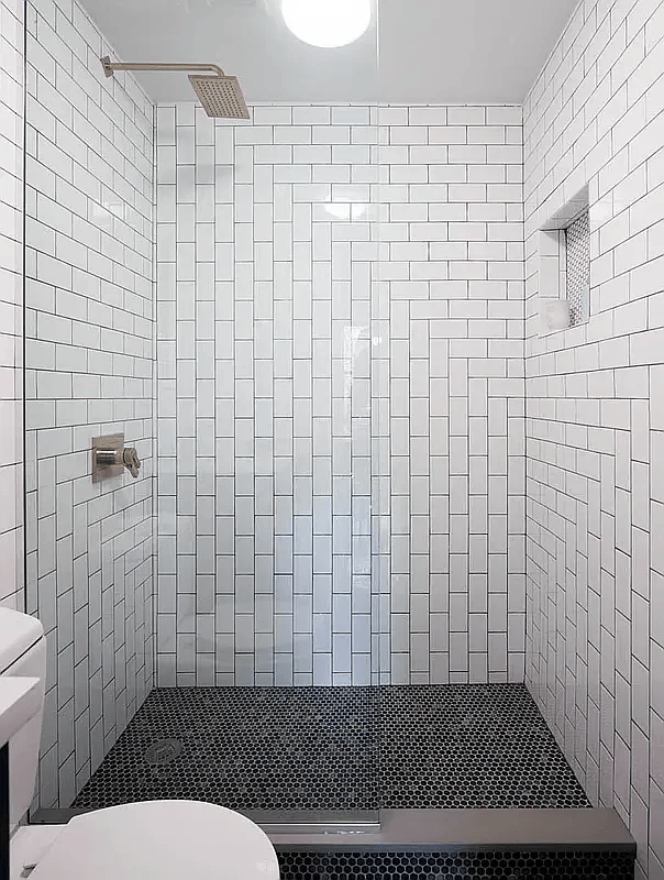 A white tiled bathroom with a toilet and a walk in shower.