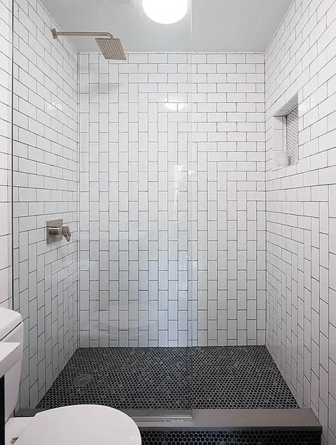 A white tiled bathroom with a toilet and a walk in shower.