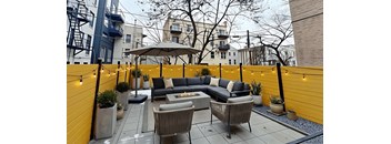 A patio with a grey sofa and a wicker chair.