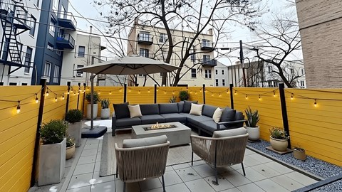A patio with a grey sofa and a wicker chair.