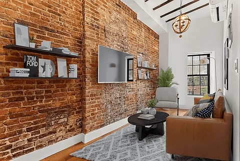 A living room with a brick wall and a brown couch.