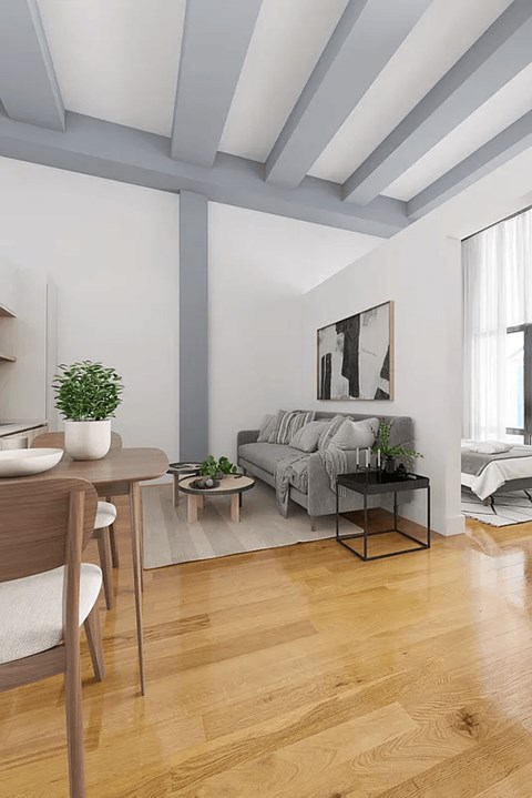 A living room with a grey couch, a wooden table, and a plant on it.