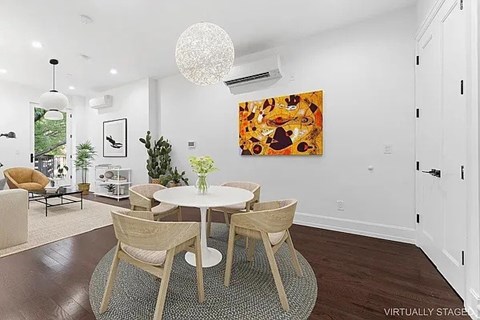 A dining room with a white table and chairs, a chandelier, and a painting on the wall.