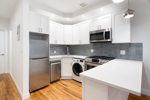 A kitchen with white cabinets and a stainless steel refrigerator.