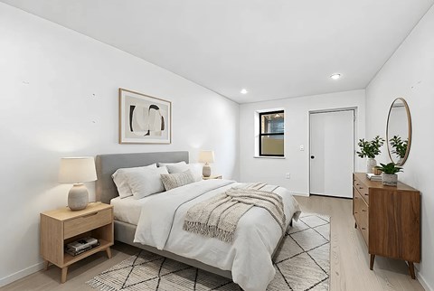 A bedroom with a bed, nightstand, and a mirror.