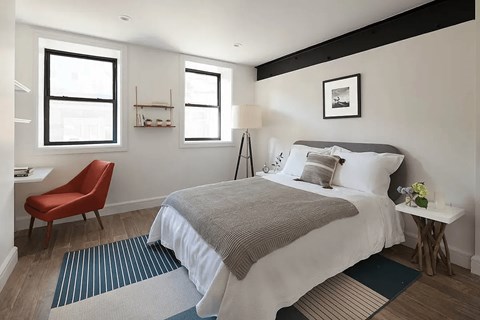 A bedroom with a large bed and a red chair.