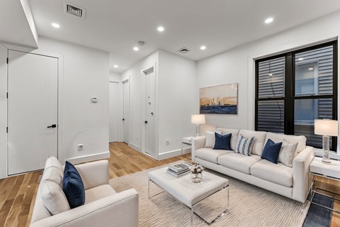 A living room with a white couch and a glass coffee table.