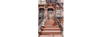A brown door is at the end of a staircase.