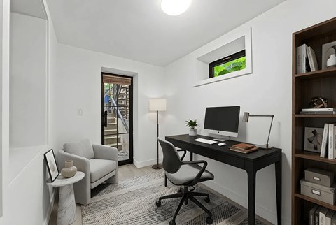 A modern home office with a desk, chair, and bookshelf.