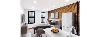 A modern bedroom with a brick wall and a bed with a grey blanket.