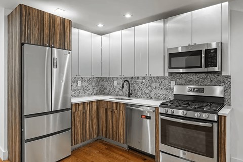 A modern kitchen with a stainless steel refrigerator, microwave, and oven.