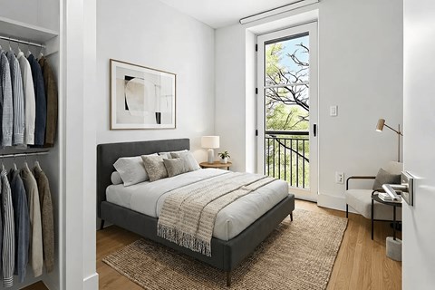 A bedroom with a bed, a chair, and a window with a view of trees.
