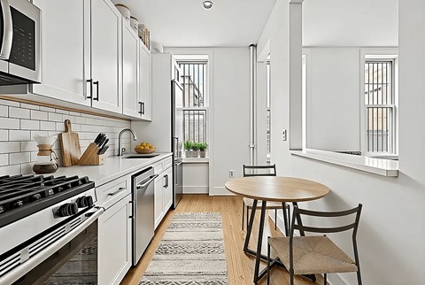 A kitchen with a stove, oven, and a table with two chairs.