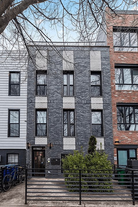 A grey building with a black gate in front.