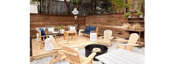 A patio with a fire pit and chairs.