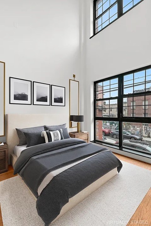 A bedroom with a large bed and a window overlooking a city street.