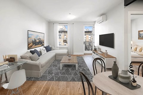 A living room with a grey couch and a painting on the wall.
