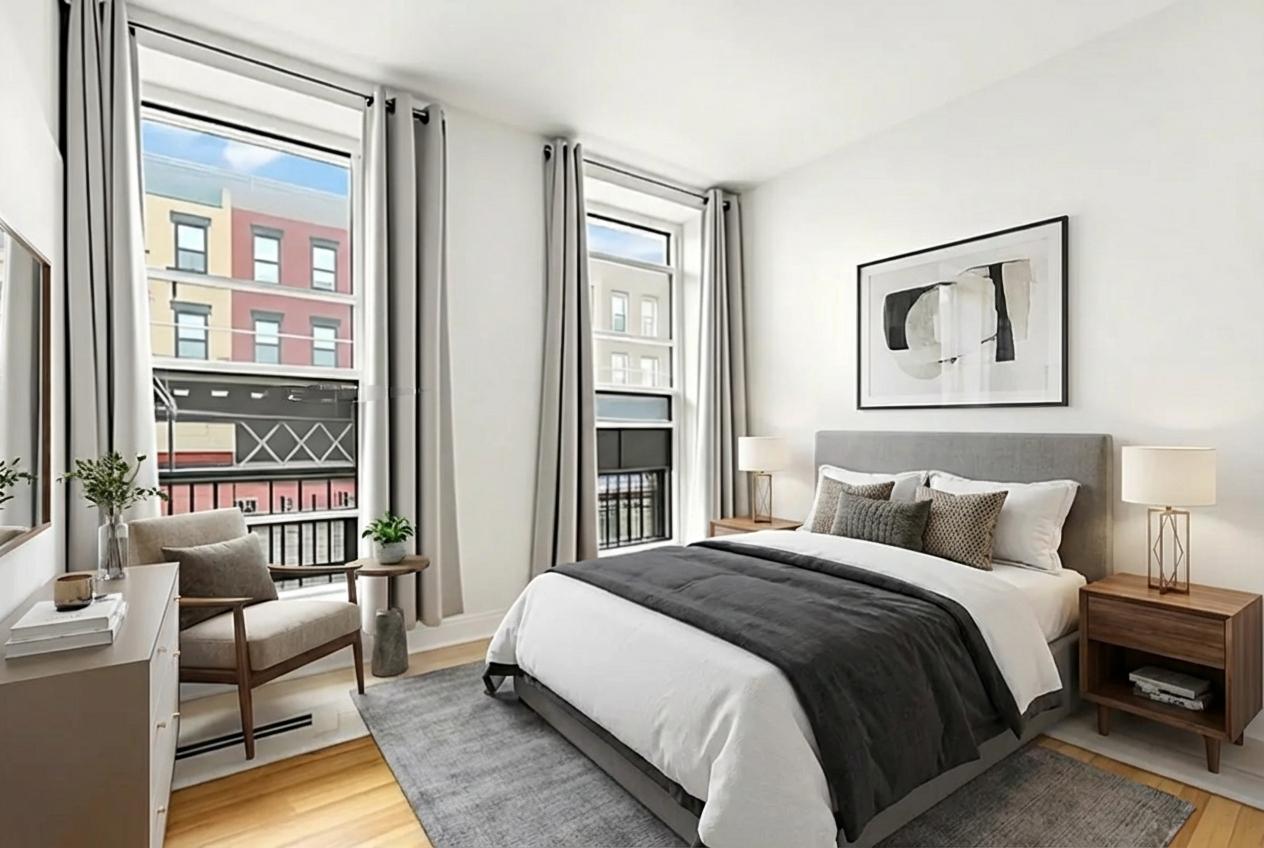 A bedroom with a large bed, a chair, and a window overlooking a balcony.