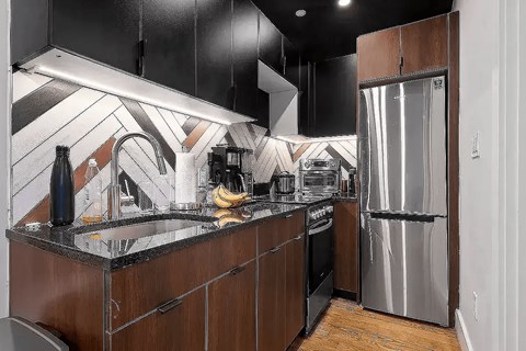 A kitchen with a black counter top and wooden cabinets.