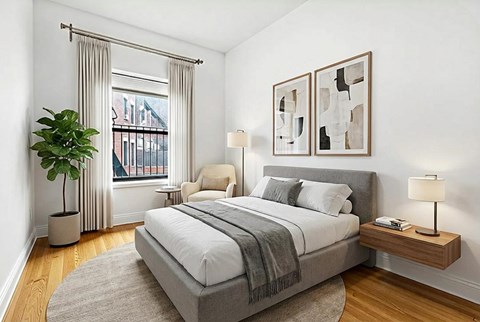 A bedroom with a large bed and a window with curtains.