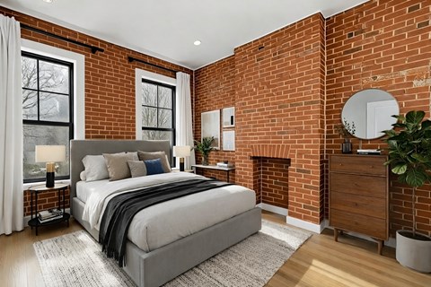 A bedroom with a large bed and a brick wall.