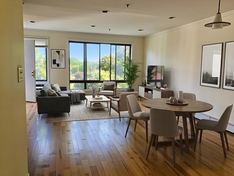 A modern living room with a large window and a dining table set for four.