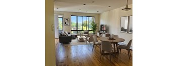 A modern living room with a large window and a dining table set for four.