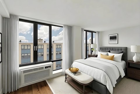 A bedroom with a large bed, a window with a view of a cityscape, and a nightstand with a lamp.