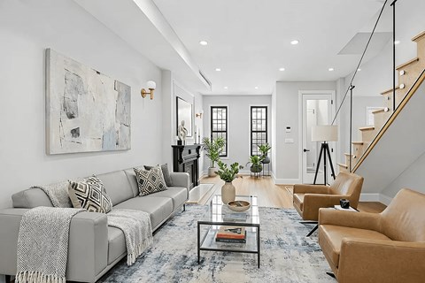 A living room with a grey couch, a coffee table, and a painting on the wall.