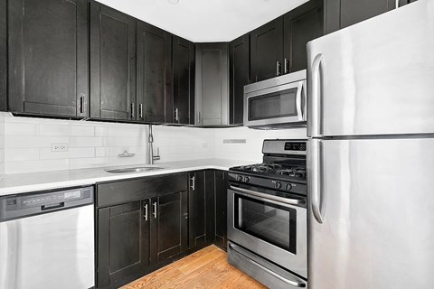 A kitchen with black cabinets and stainless steel appliances.