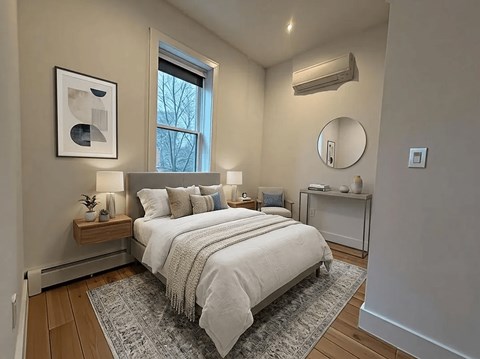A bedroom with a bed, nightstand, and a window.