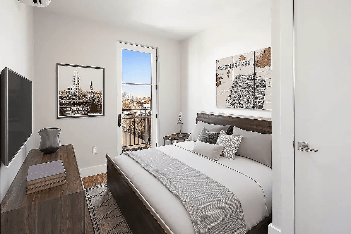 A bedroom with a large bed and a balcony overlooking a city.