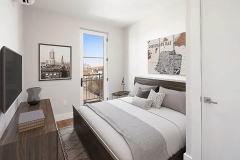 A bedroom with a large bed and a balcony overlooking a city.