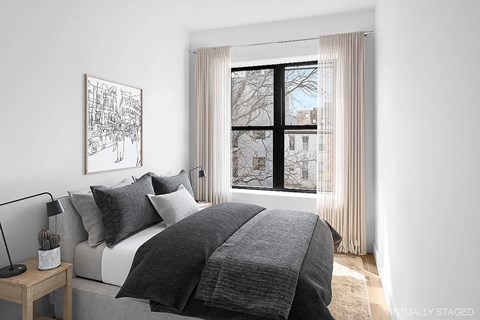 A bedroom with a large bed and a window with curtains.