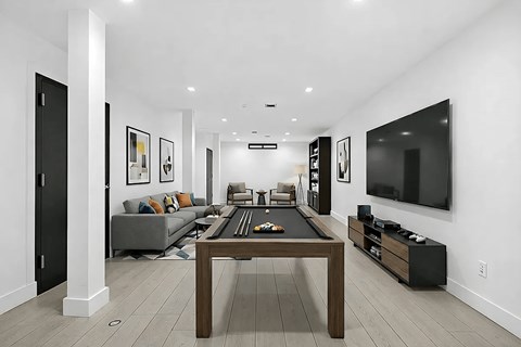 A modern living room with a pool table and a television.