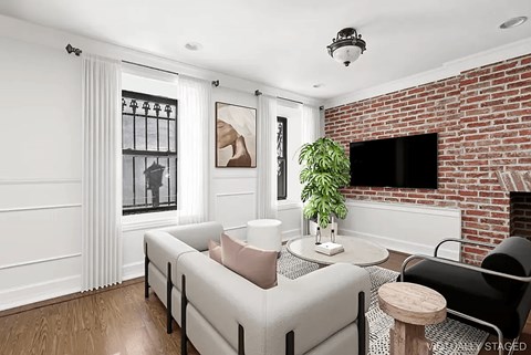 A living room with a white couch and a brick fireplace.