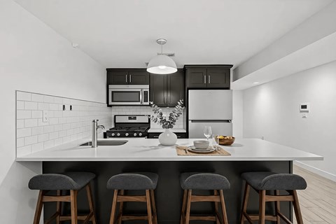 A modern kitchen with a white countertop and grey bar stools.