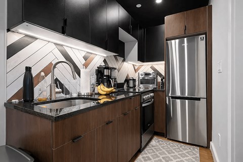 A modern kitchen with a black and white tiled backsplash.