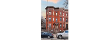 Two cars parked in front of a red brick building.
